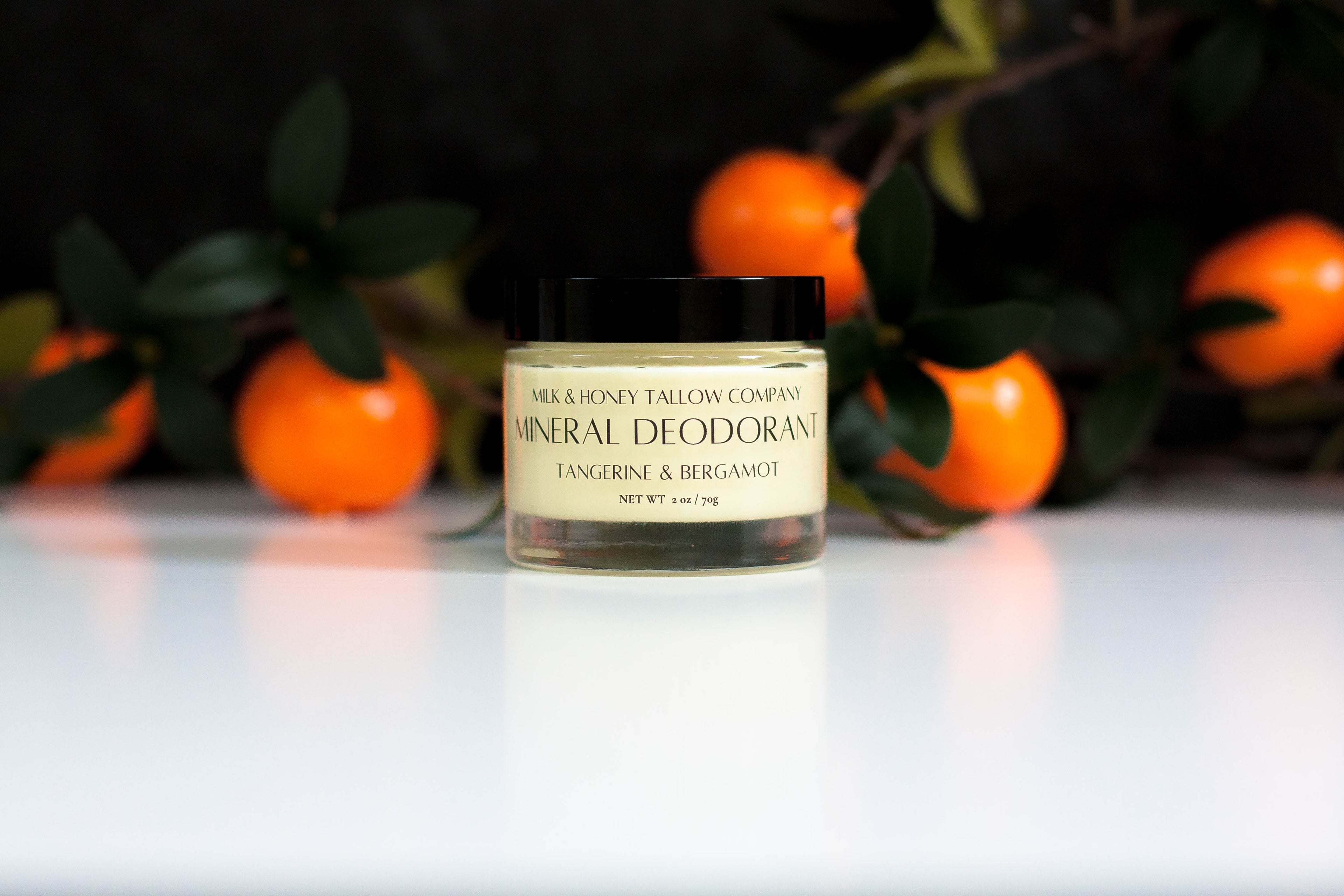 Jar of Tangerine & Bergamot mineral deodorant with tangerines and leaves in the backgound