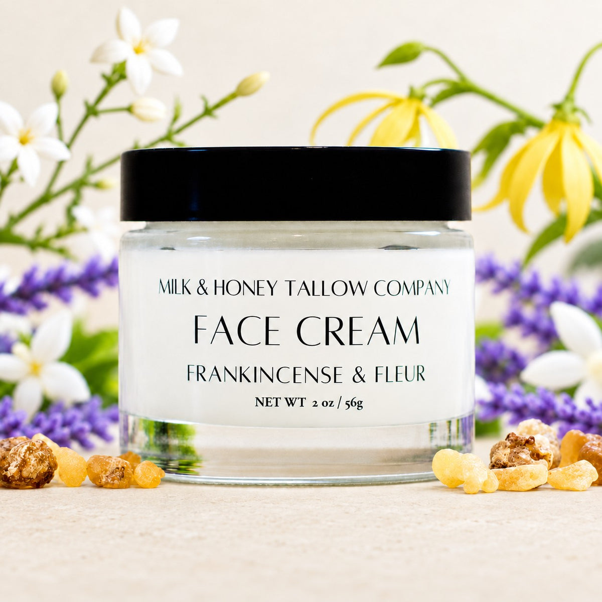 glass jar of frankincense and fleur tallow face cream with botanicals of ylang ylang, jasmine, lavender, and frankincense displayed around it