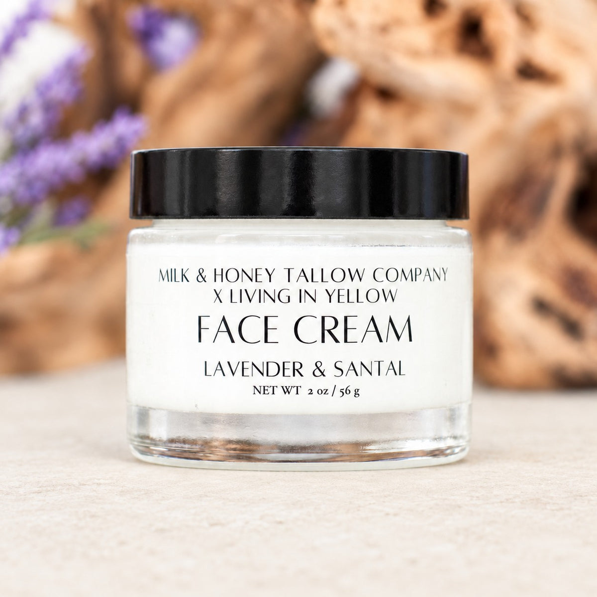 Glass jar of Lavender & Santal tallow face cream with wood and lavender displayed in the background