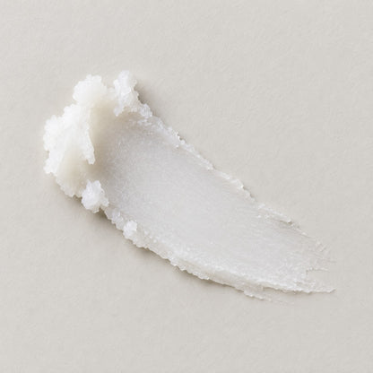A smear of white, luxury lip butter on a light beige background.