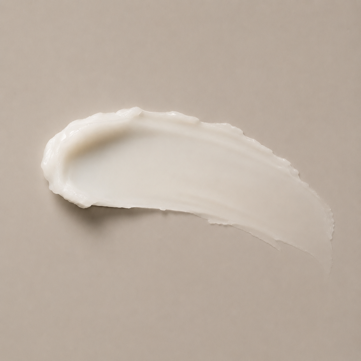 A thick, creamy off-white cosmetic smear of luxury face cream on a solid taupe-beige background.