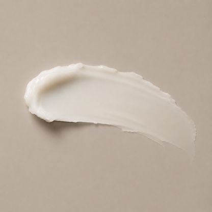 A thick, creamy off-white cosmetic smear of luxury face cream on a solid taupe-beige background.