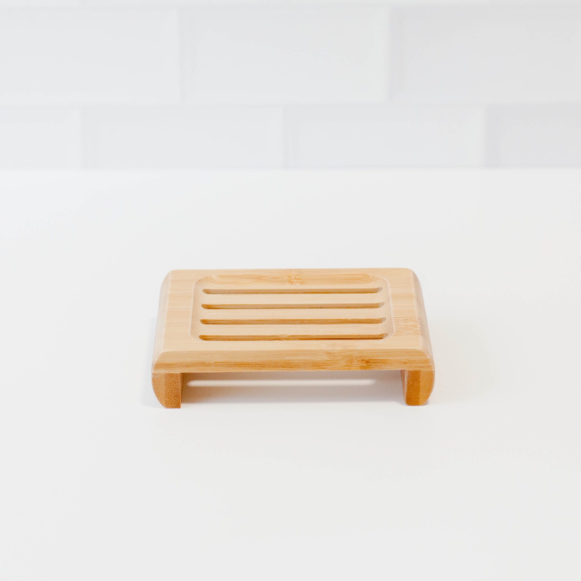 Bamboo soap stands on white counter with white tile backsplash