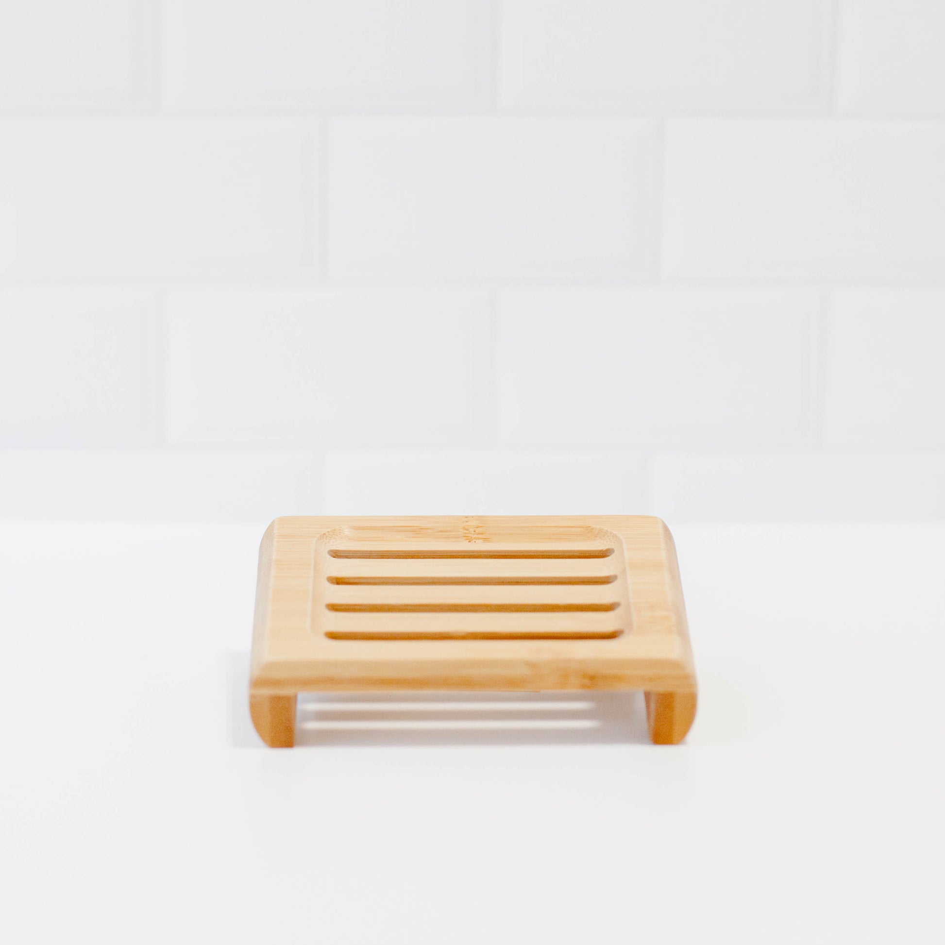 Bamboo soap stand on white counter with white tile backsplash