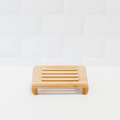 Bamboo soap stand on white counter with white tile backsplash