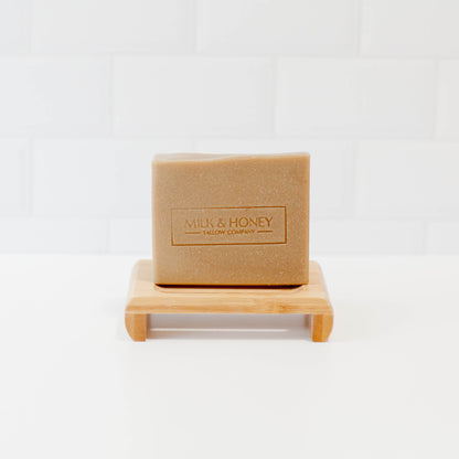 Bamboo soap stand with bar of soap on white counter with white tile backsplash