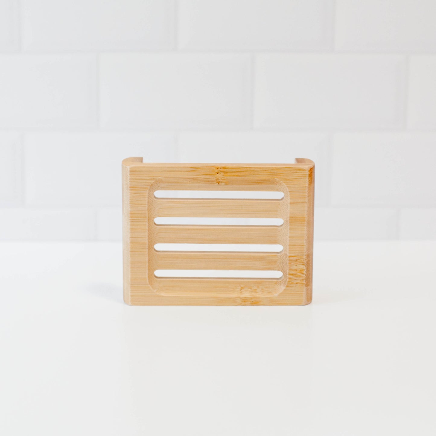 Bamboo soap stand upright to see slats on white counter with white tile backsplash