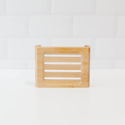 Bamboo soap stand upright to see slats on white counter with white tile backsplash