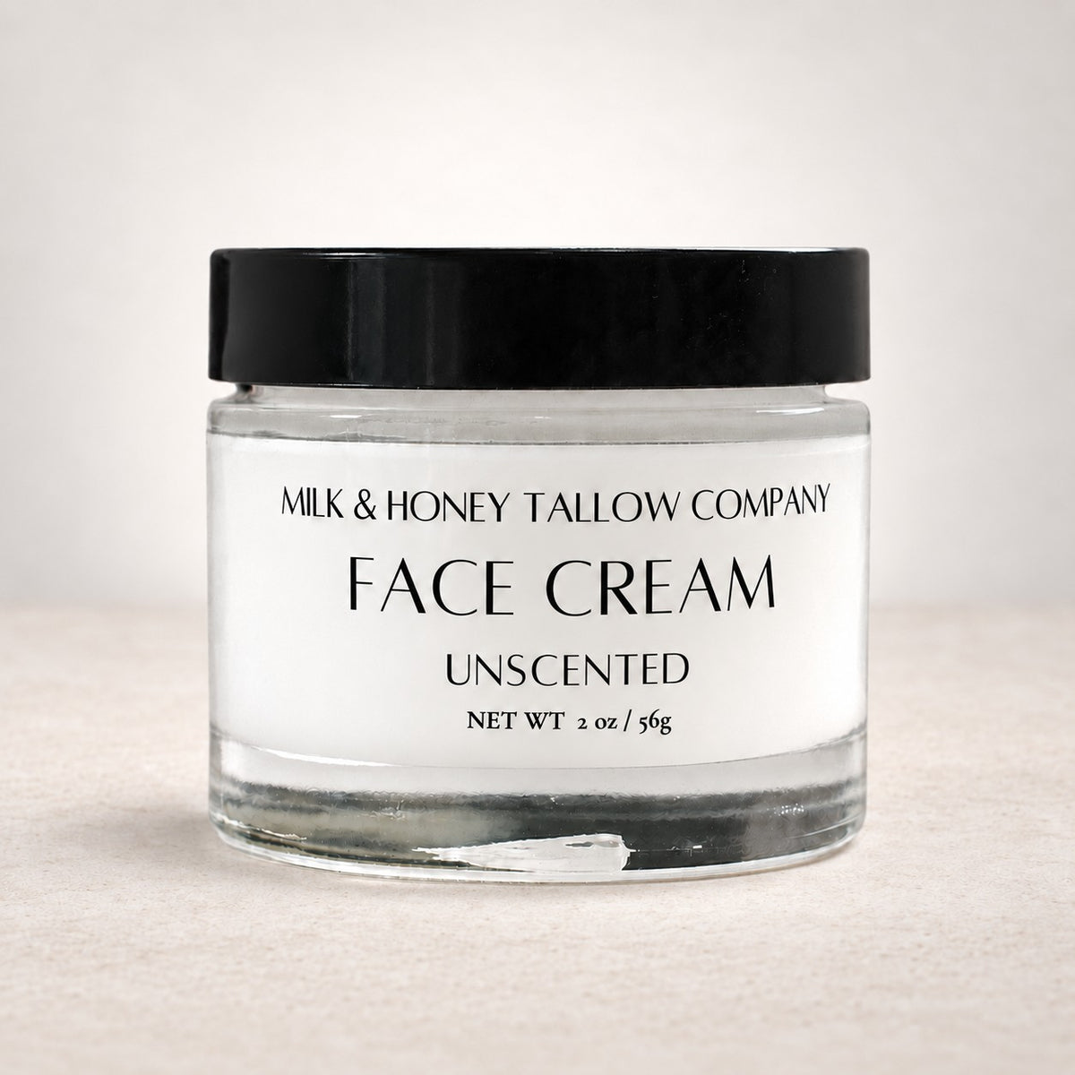 Glass jar of unscented tallow face cream on a white background