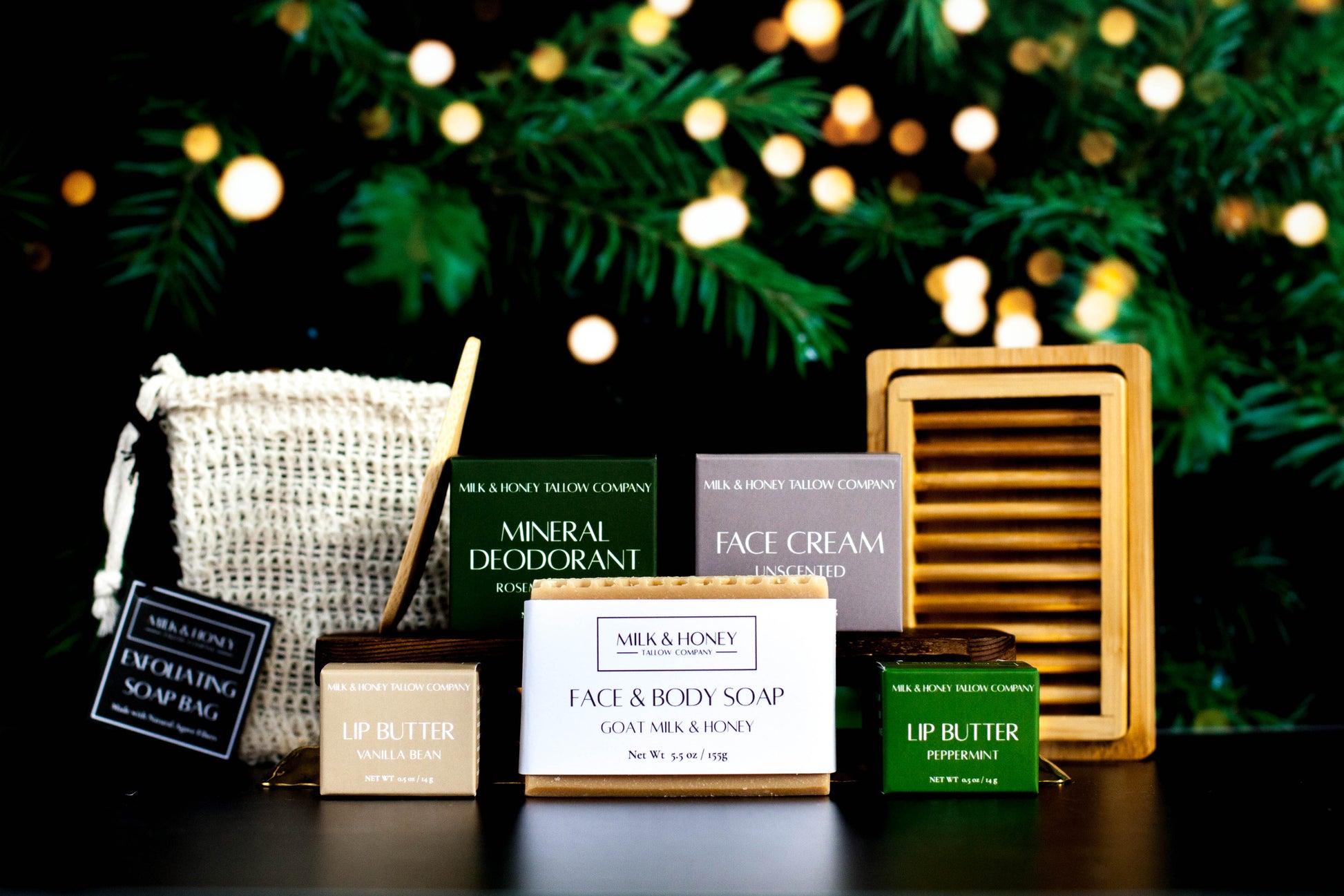 Collection of natural tallow skincare products with a festive background featuring lights and greenery.