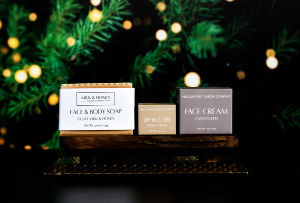 Milk & Honey natural tallow skincare products on a wooden stand with Christmas lights and greenery in the background